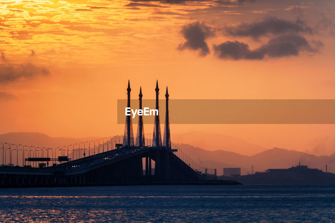 Bridge over river against sky during sunset