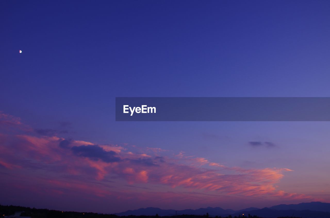 LOW ANGLE VIEW OF SILHOUETTE MOON AGAINST BLUE SKY