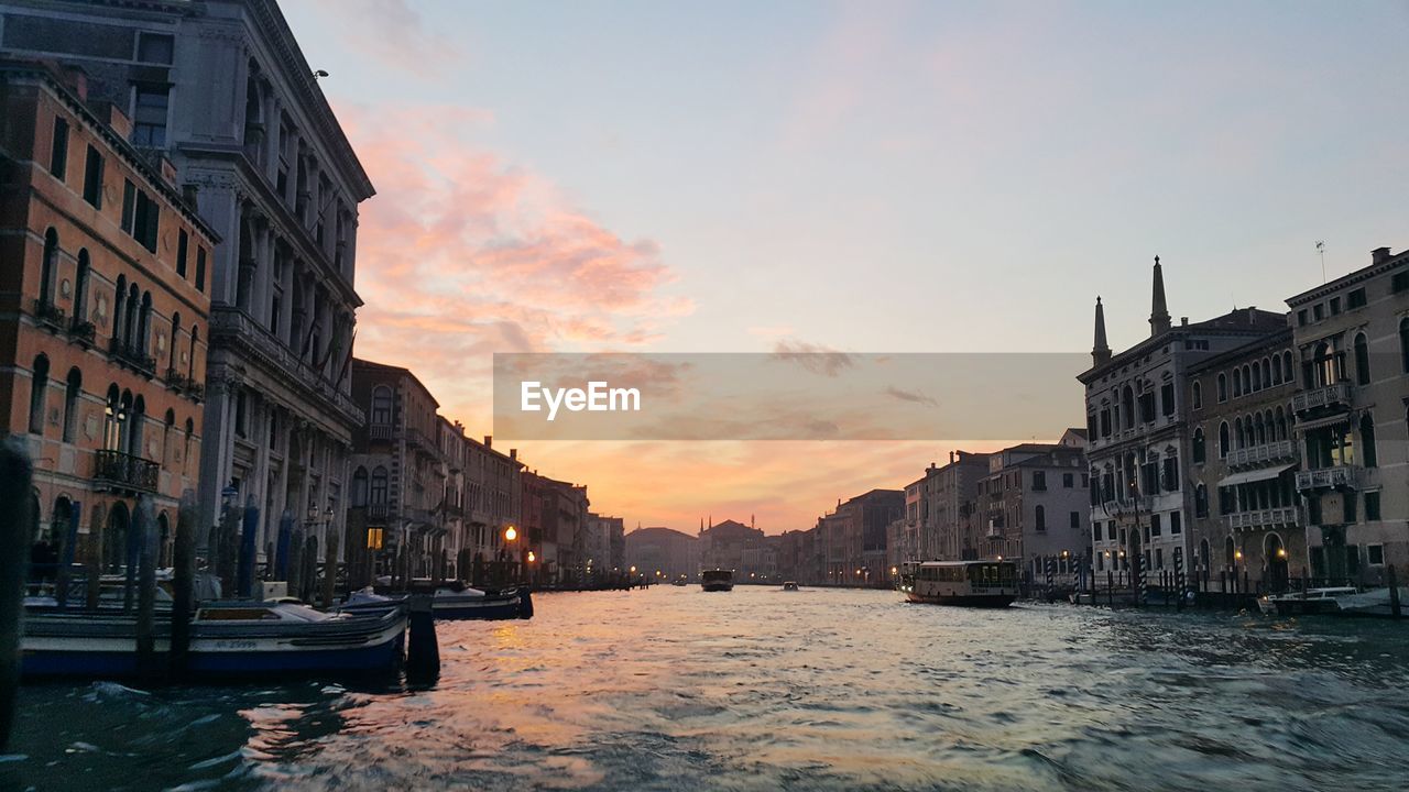 Canal passing through city at sunset