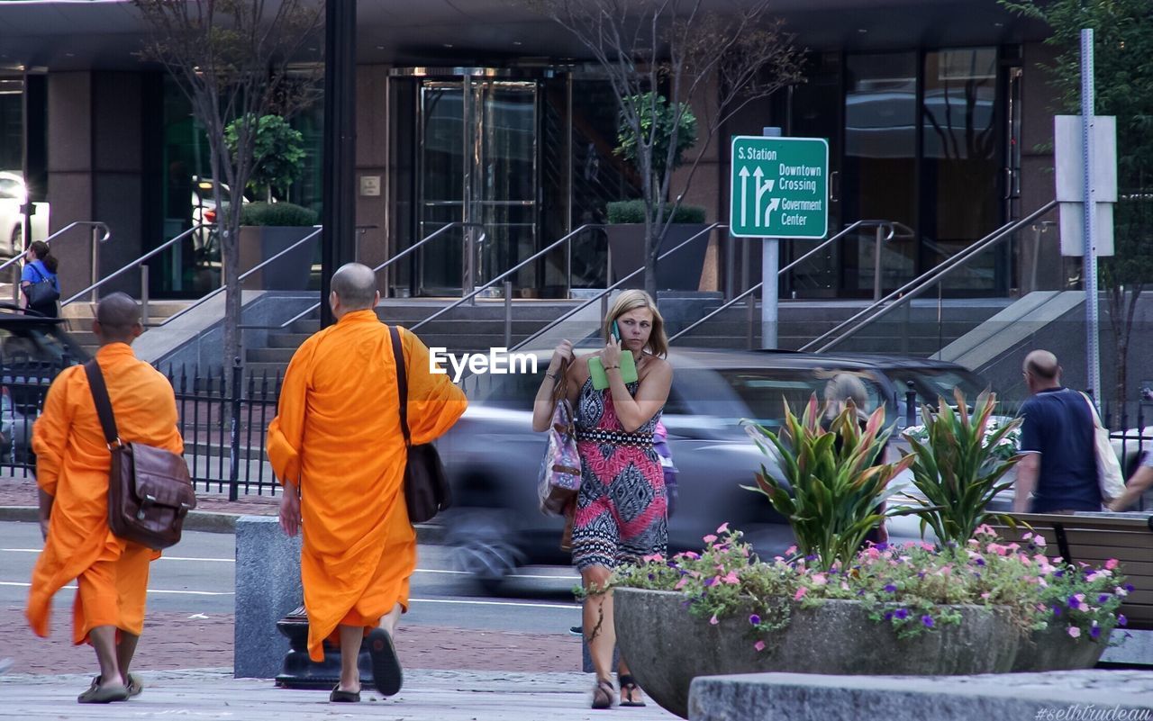 REAR VIEW OF PEOPLE WALKING ON STREET