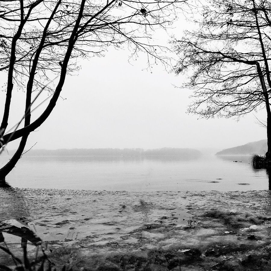 Scenic view of lake against clear sky in foggy weather