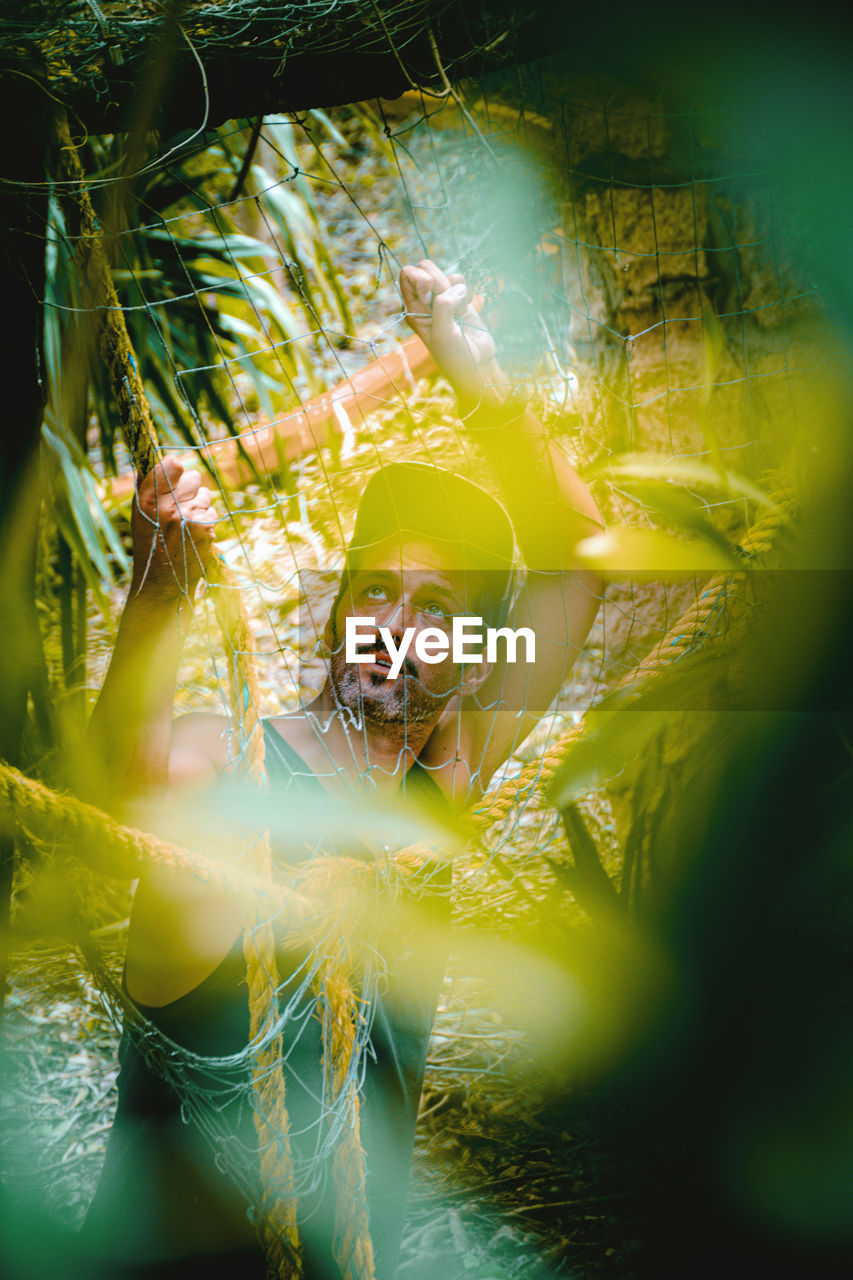 Man in forest seen through net