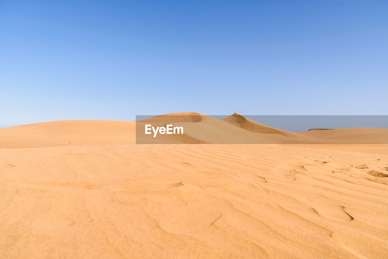 Scenic view of desert against clear blue sky