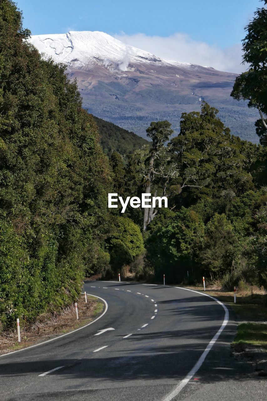 Road by trees and mountains against sky