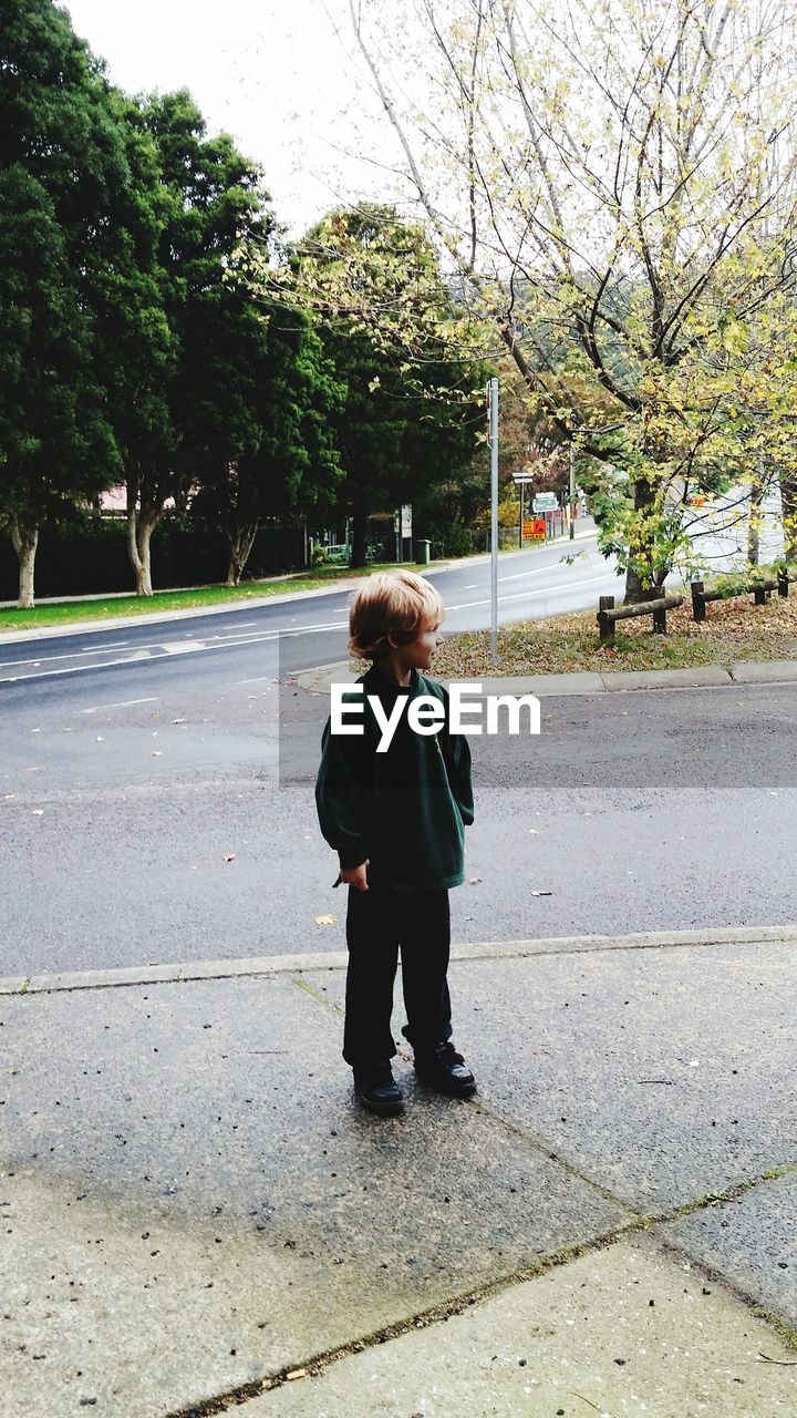 Full length of boy standing on sidewalk