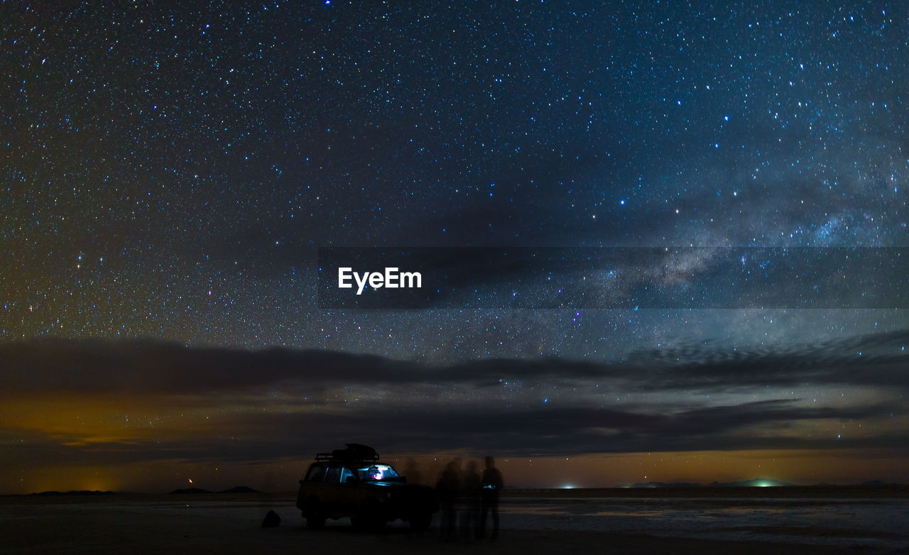 Blurred motion of people by off-road vehicle at salar de uyuni against constellation
