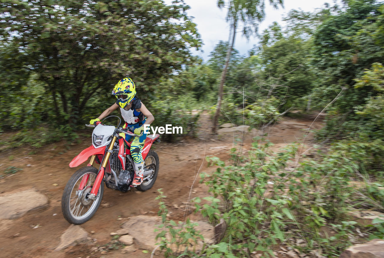 Woman riding her dirt-bike on forest track in pak chong / thailand