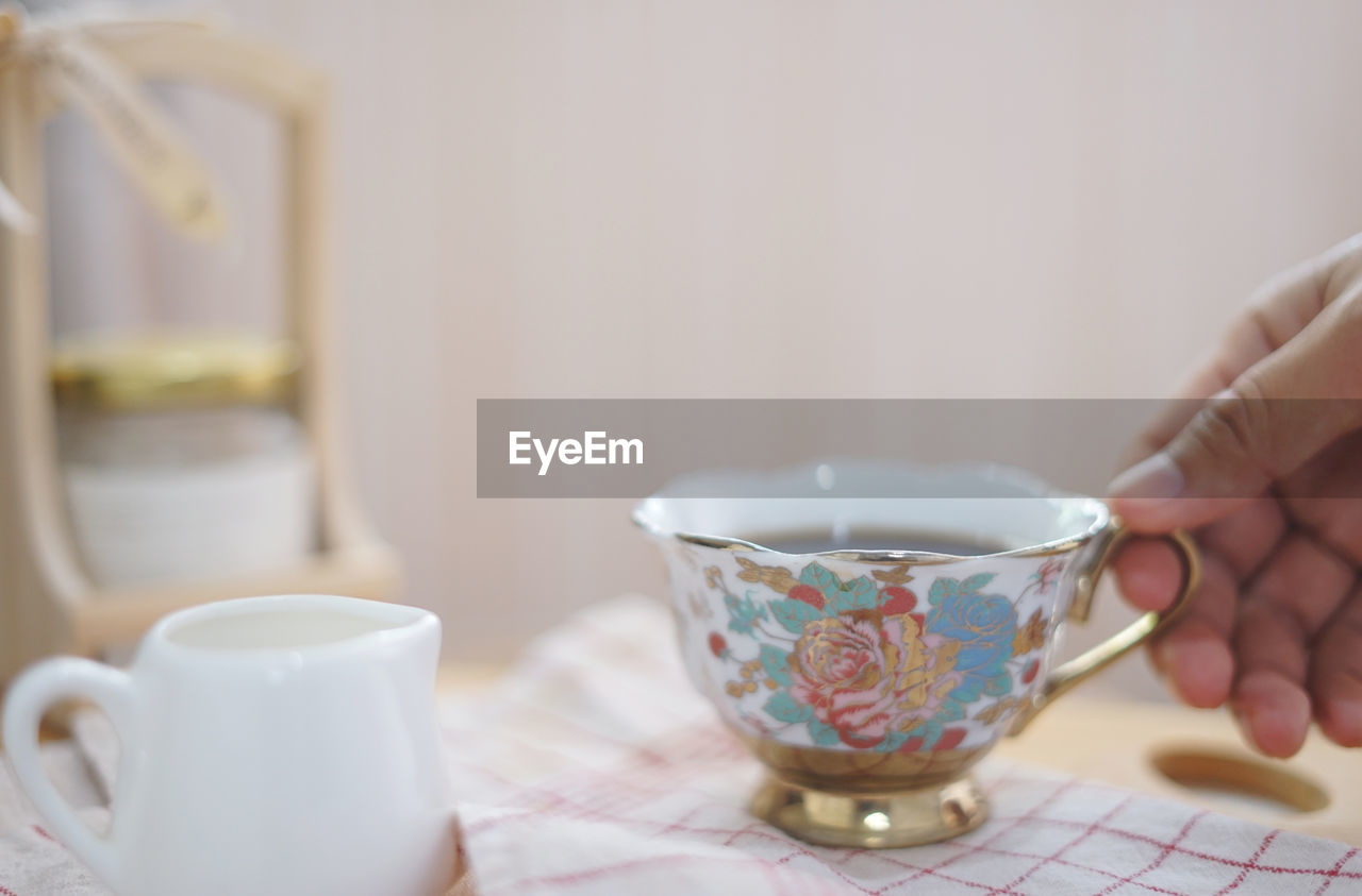 CLOSE-UP OF HUMAN HAND HOLDING COFFEE CUP