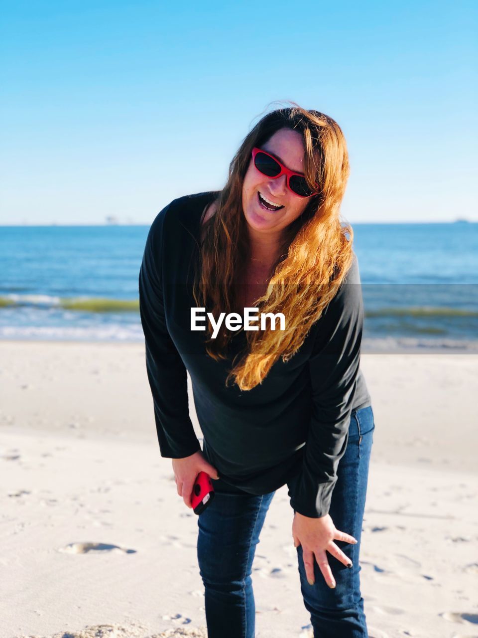 Portrait of happy mature woman wearing sunglasses at beach