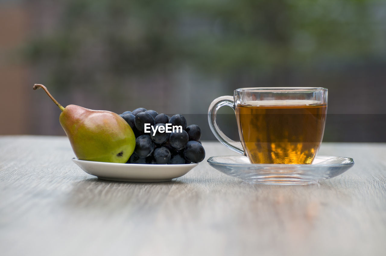 FRUITS IN GLASS ON TABLE AGAINST WOODEN CONTAINER