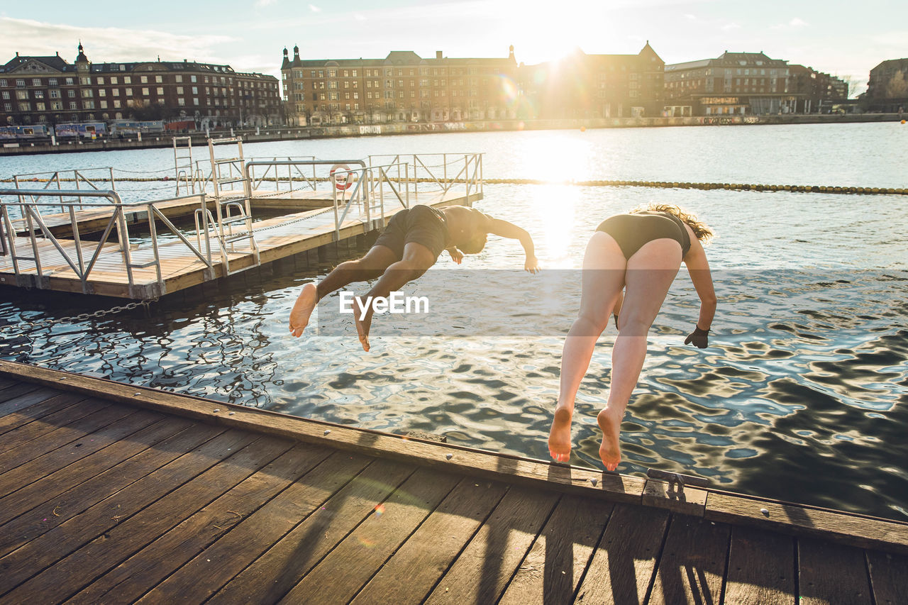 Two friends of different age and race jumping in cold water in denmark