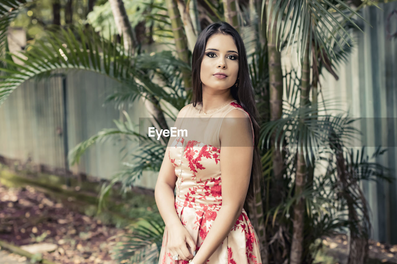 PORTRAIT OF BEAUTIFUL YOUNG WOMAN STANDING AGAINST TREE