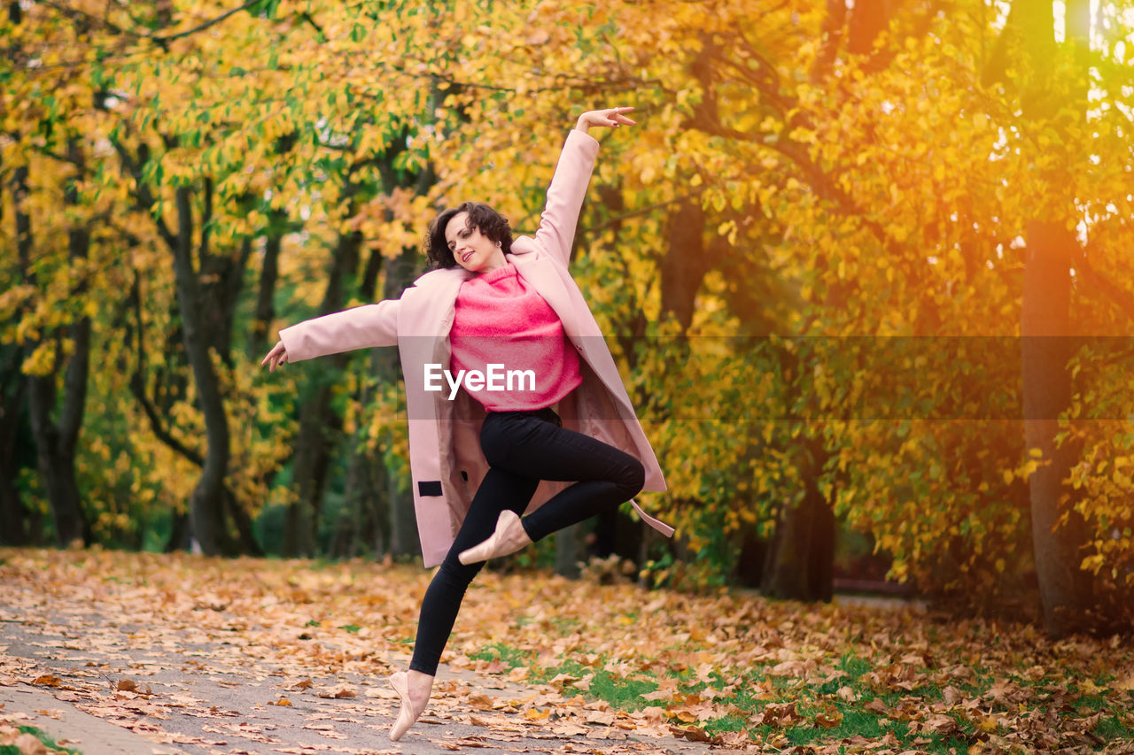 full length of young woman jumping on field