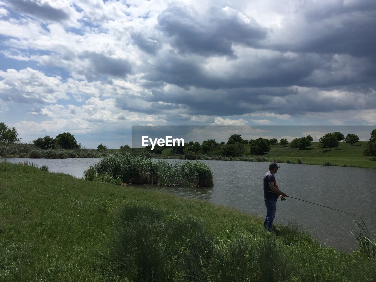 REAR VIEW OF MAN STANDING ON A LAKE