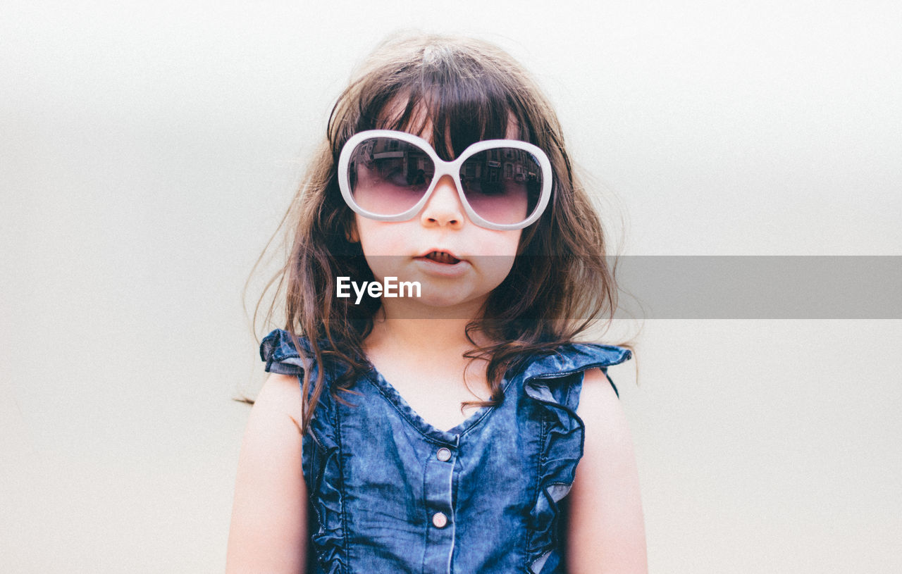 Portrait of girl wearing sunglasses against white background