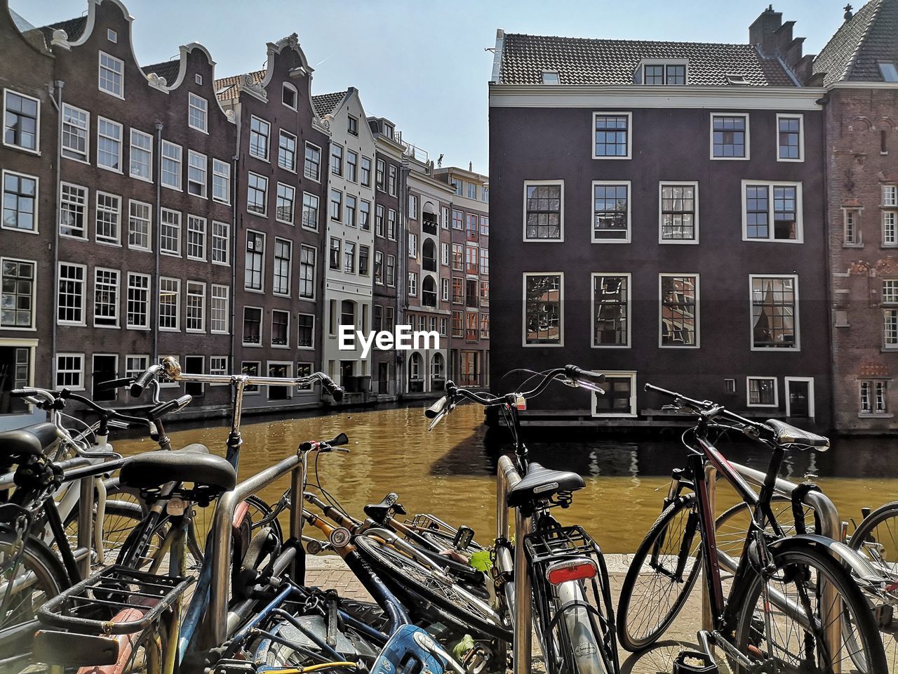 Bicycle parked by canal against buildings in city