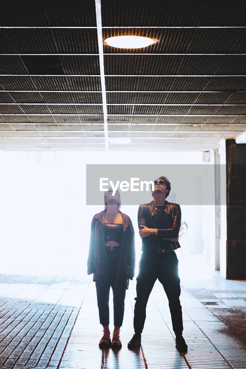 Couple looking up standing in illuminated underpass