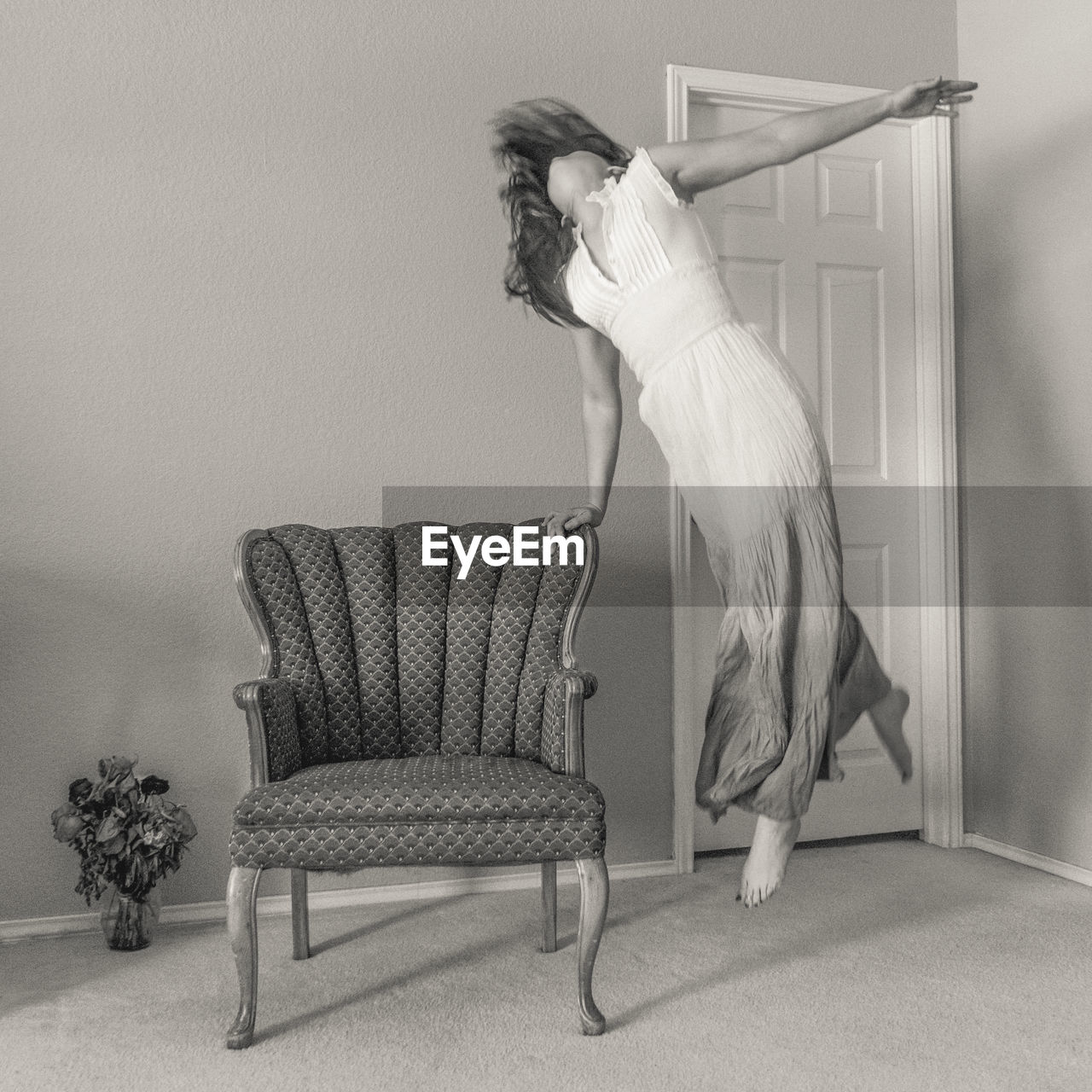 Woman dancing on floor by chair at home