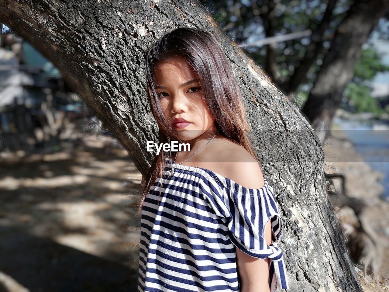 Portrait of girl standing against tree trunk