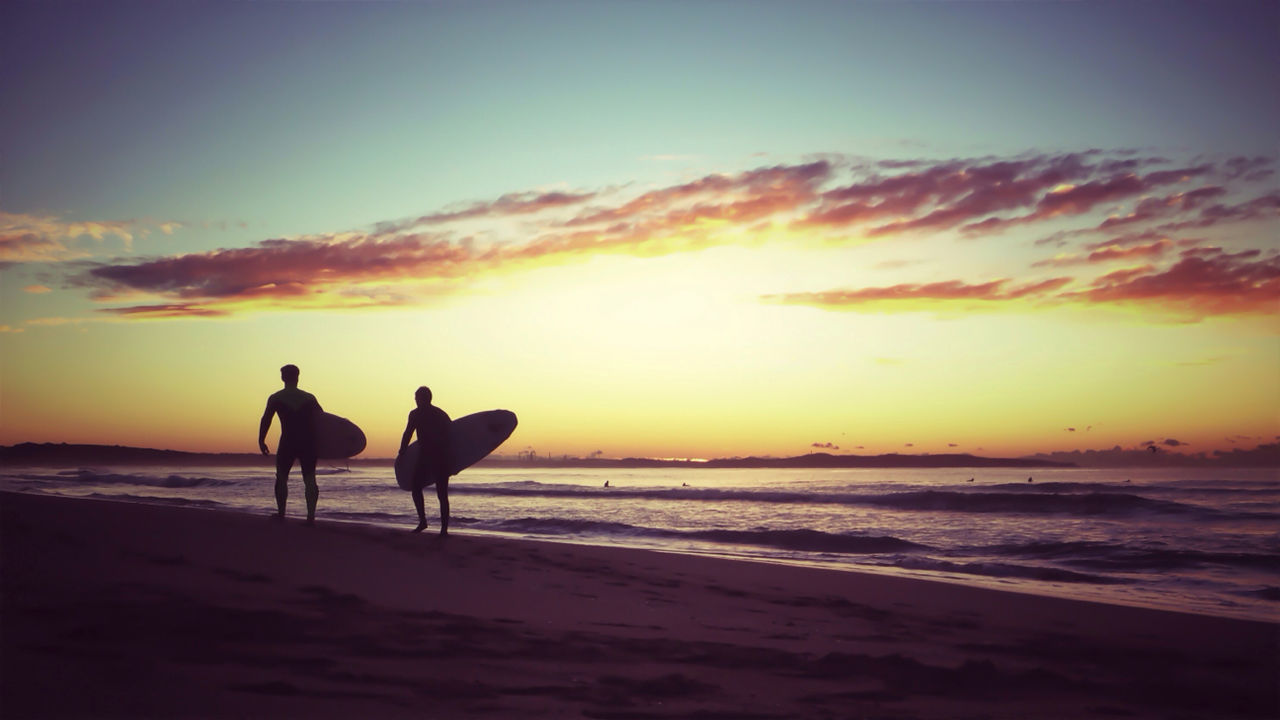 Silhouette men with surfboard walking on beach