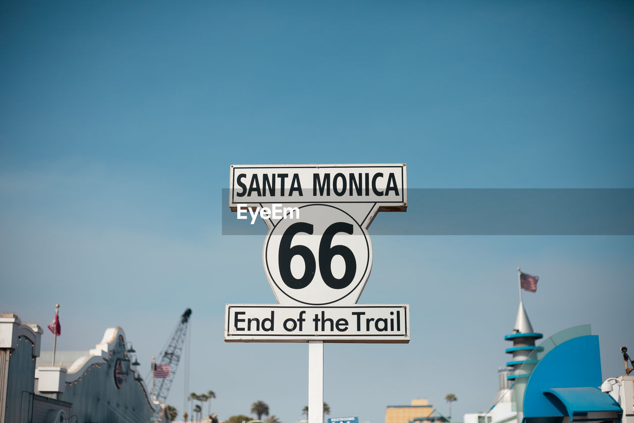 Low angle view of road sign at santa monica pier against clear sky
