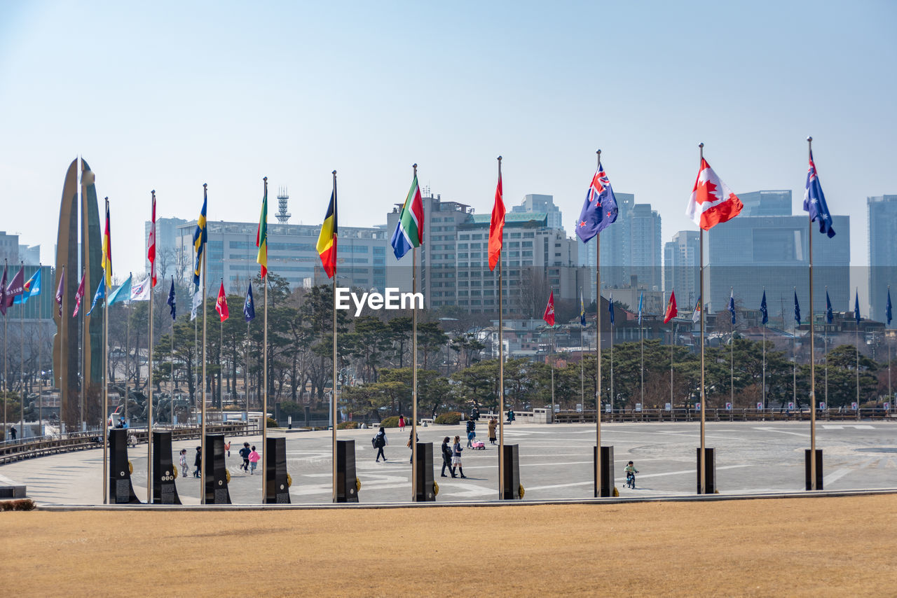 flag, sky, patriotism, nature, architecture, day, clear sky, city, travel destinations, water, outdoors, built structure, in a row, sunny, building exterior, travel, environment, no people, walkway, land, transportation, pole, beach