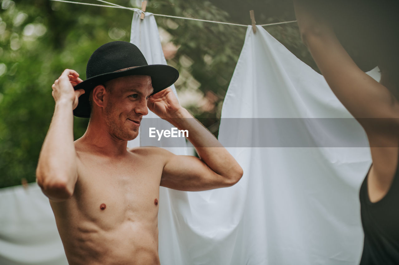 Portrait of young man with hat standing against blurred background