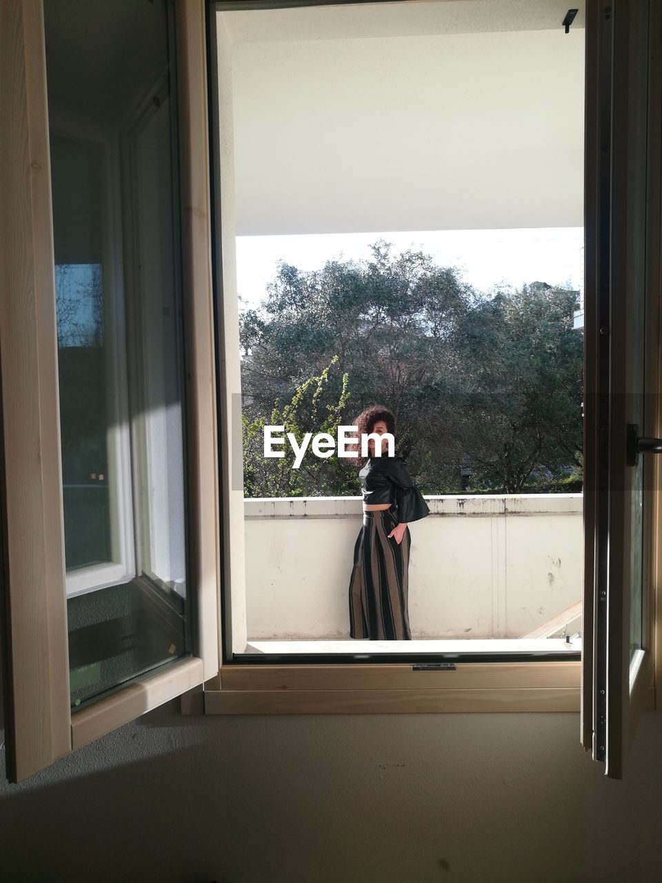 Woman standing by retaining wall seen through window