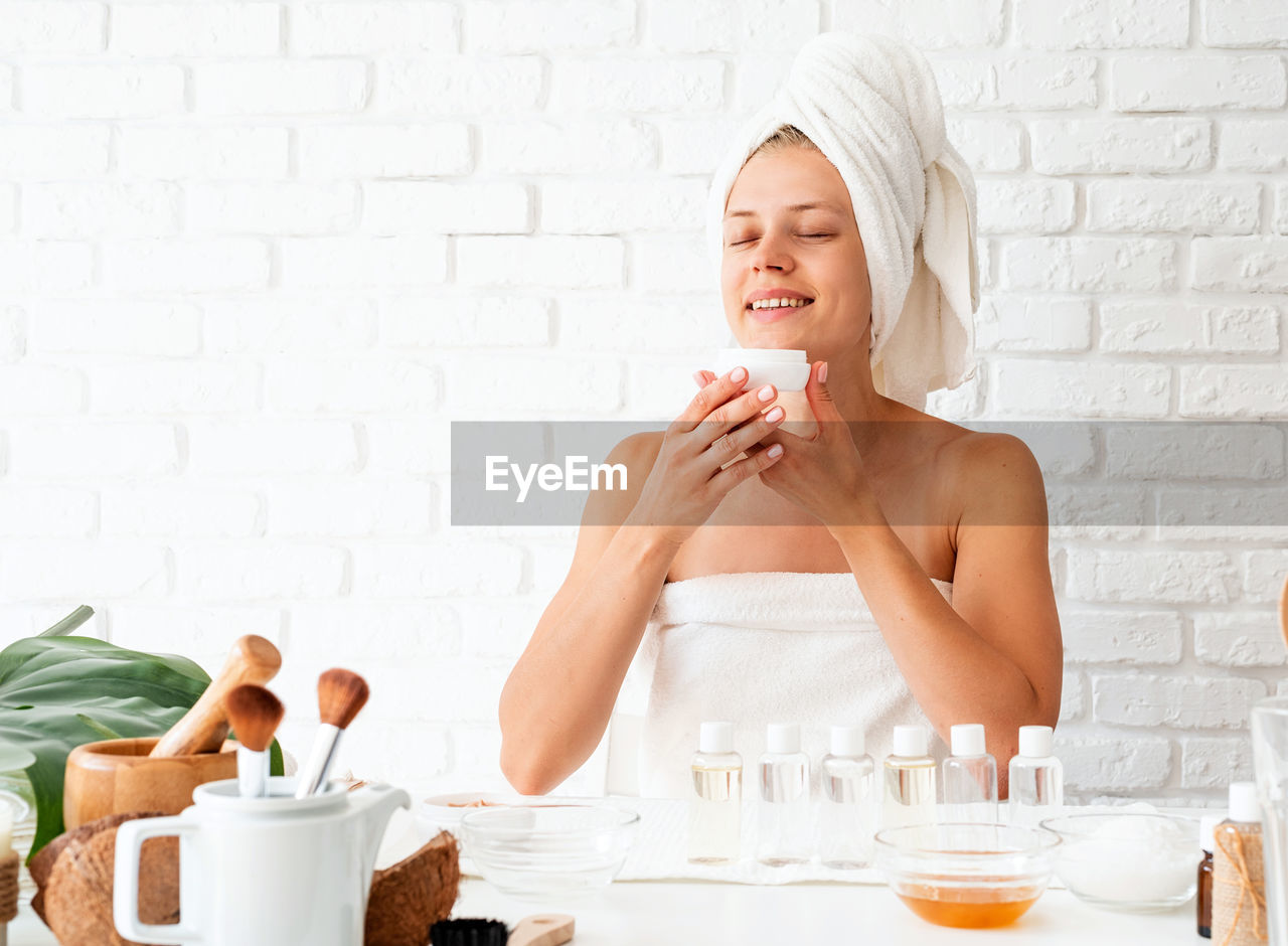  happy young woman wearing white bathrobes towels on head doing spa procedures in spa beauty salon