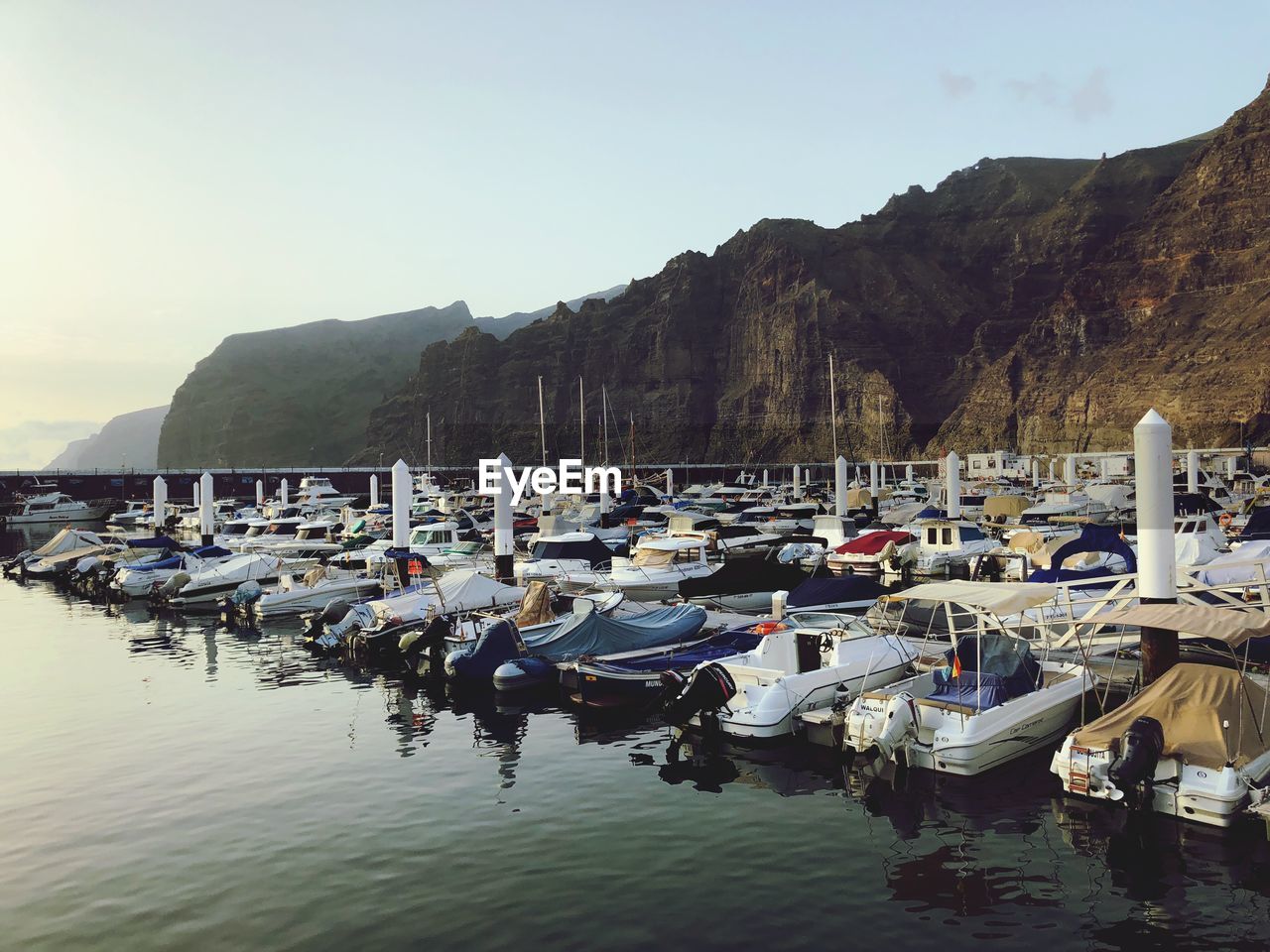 Boats moored at harbor against sky