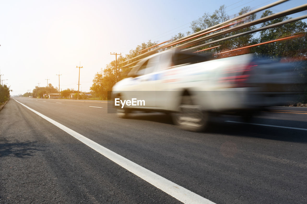 BLURRED MOTION OF VEHICLES ON ROAD AGAINST SKY