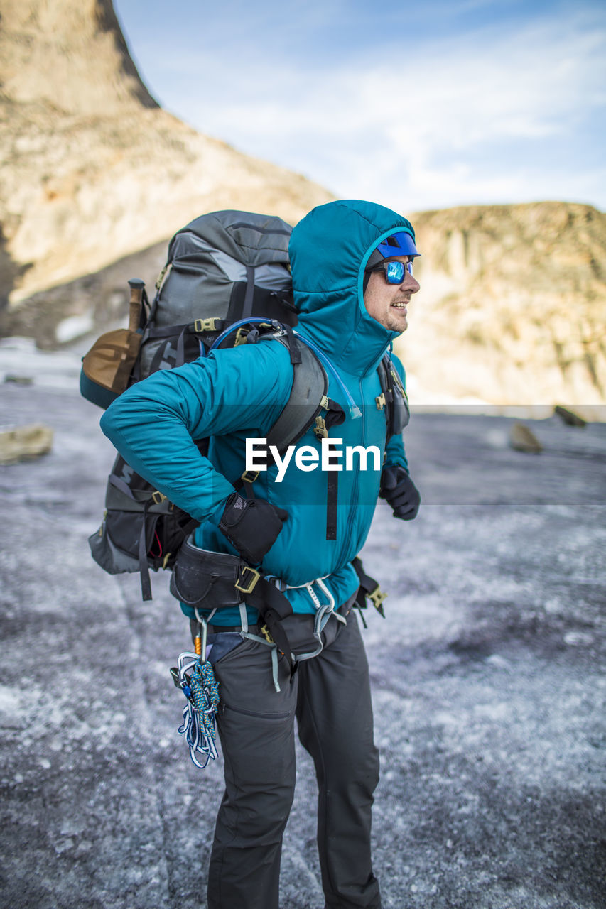 Mountain climber straps on heavy backpack during multi-day trip.