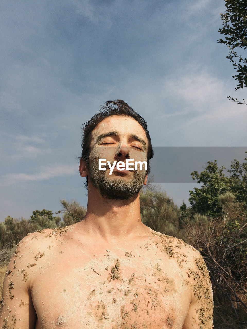 Shirtless dirty young man at beach against sky