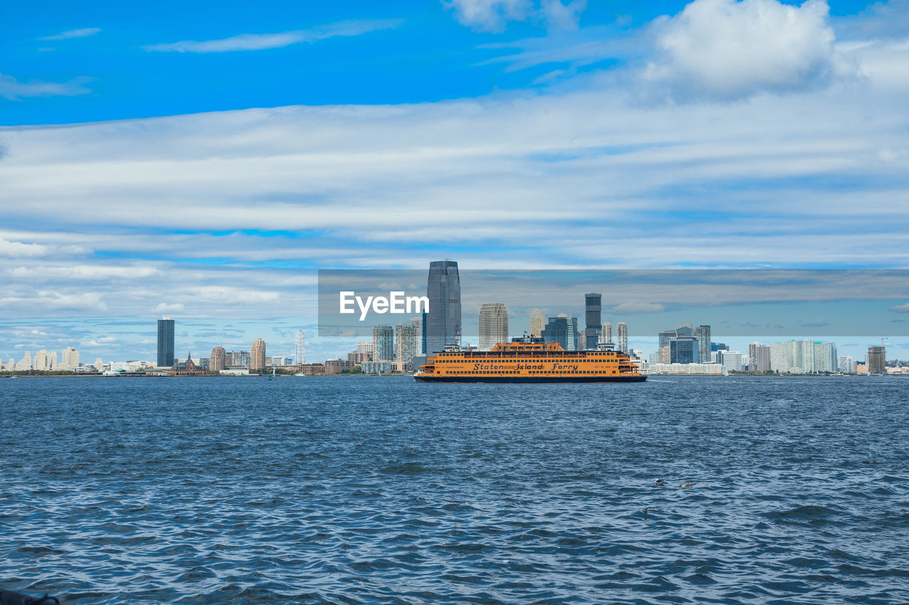 VIEW OF CALM SEA WITH BUILDINGS IN BACKGROUND