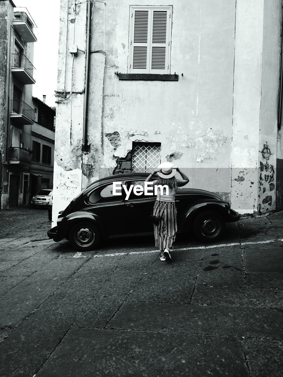 Rear view of woman walking towards vintage car parked on street