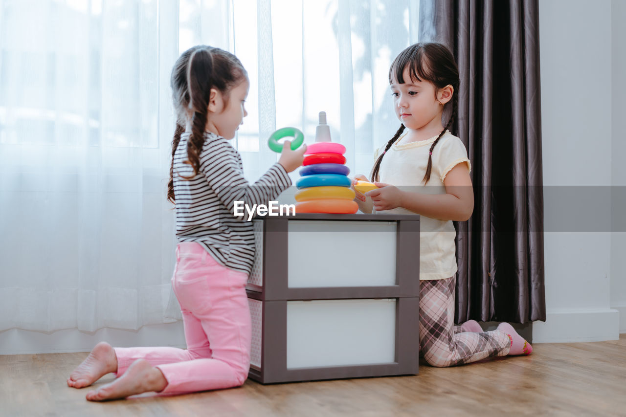 Sisters playing with multi colored toys at home