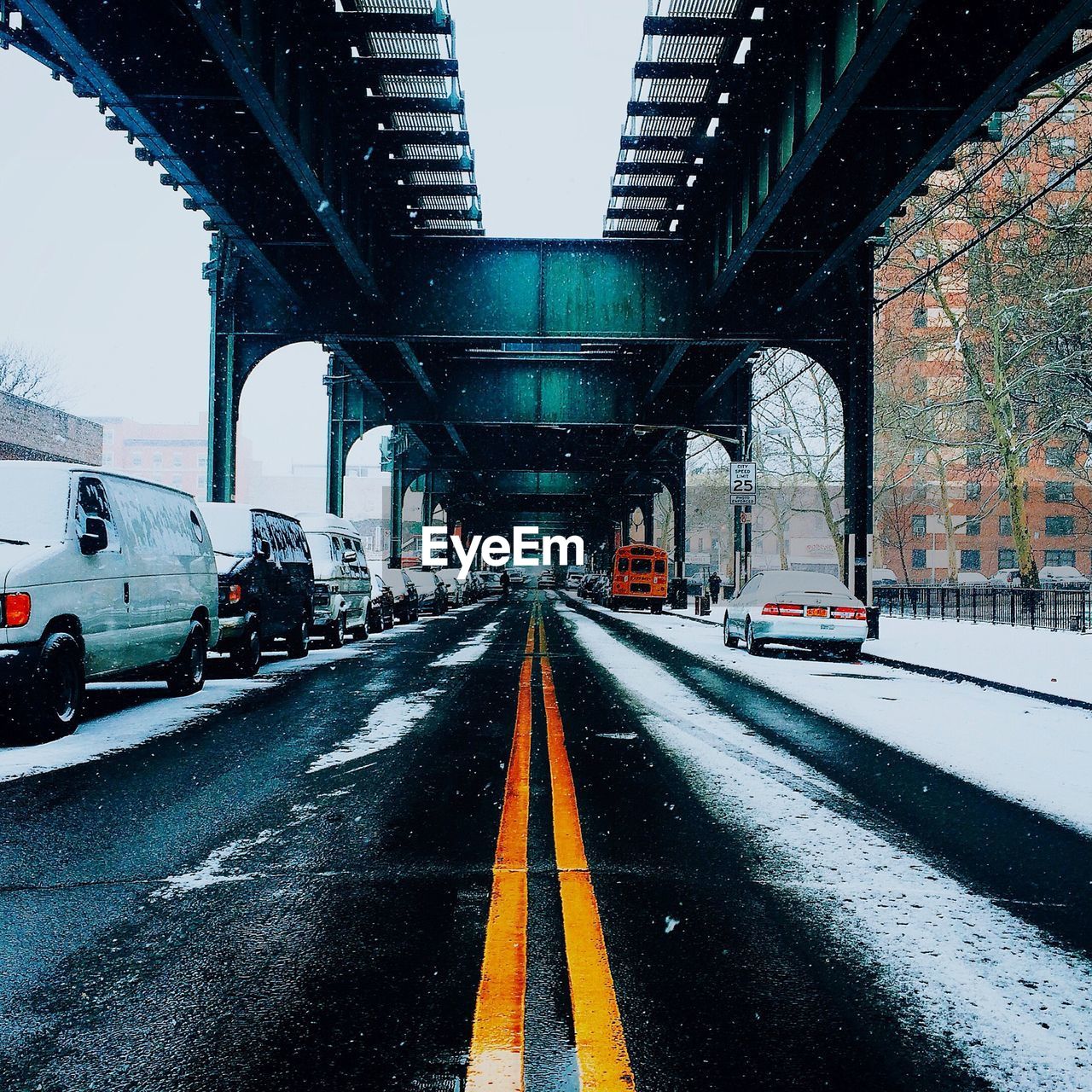 Road amidst car parked under bridge