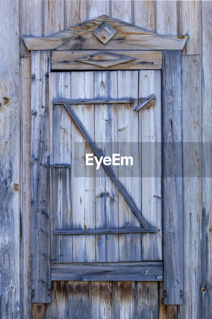 Spare wooden door in an old wooden house. front view.