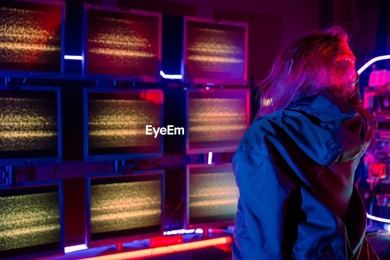 side view of young woman looking away while standing at night