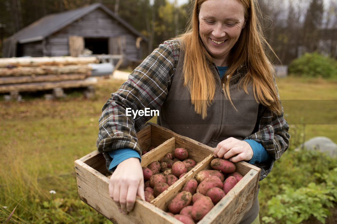 Woman holding wooden crate with potatoes