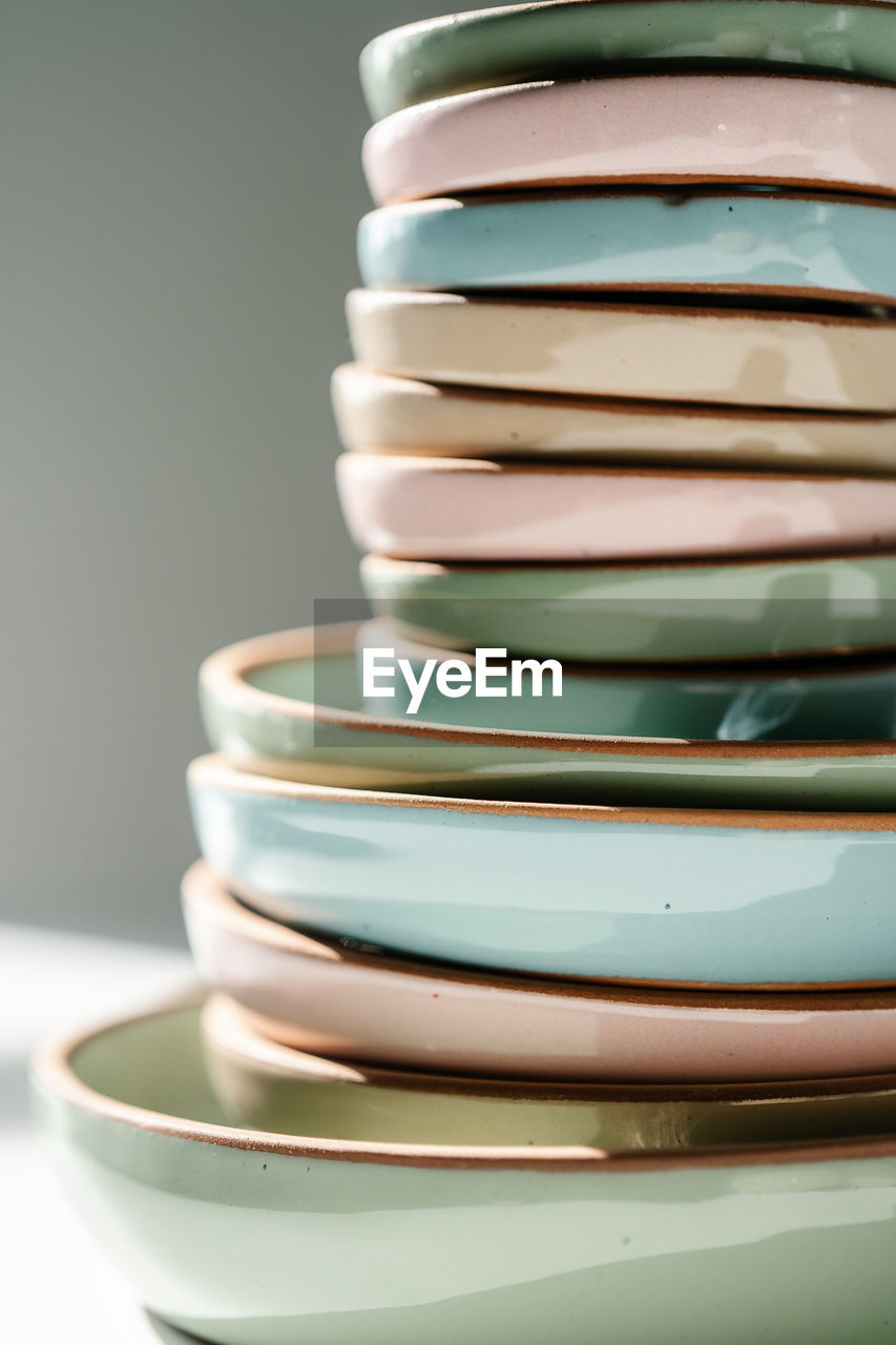 A large stack of ceramic cups in pastel colors.