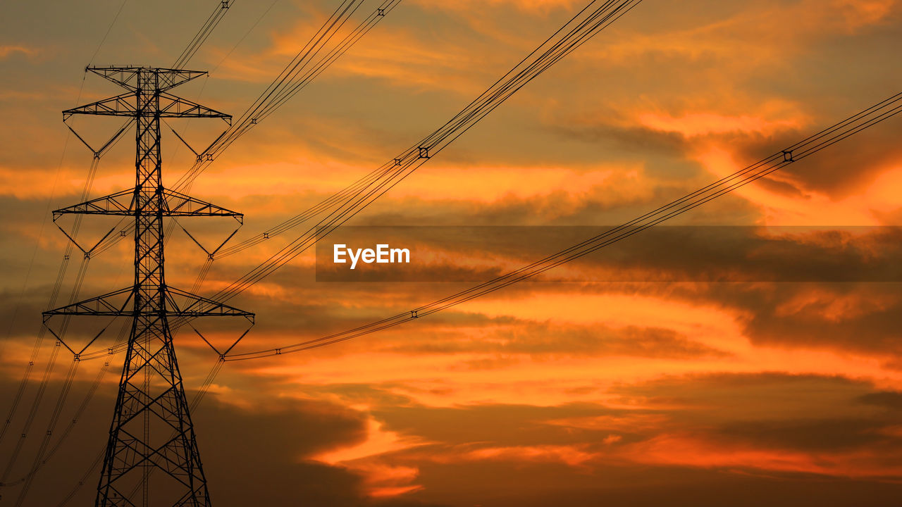 LOW ANGLE VIEW OF SILHOUETTE ELECTRICITY PYLONS AGAINST DRAMATIC SKY