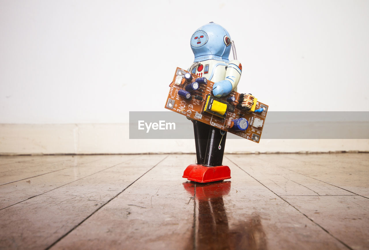 CLOSE-UP OF TOY ON FLOOR AGAINST WALL