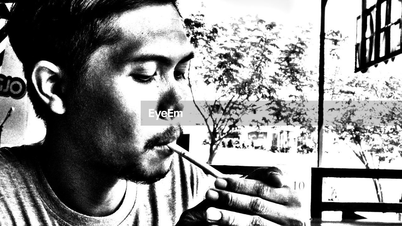 PORTRAIT OF MAN SMOKING CIGARETTE OUTDOORS