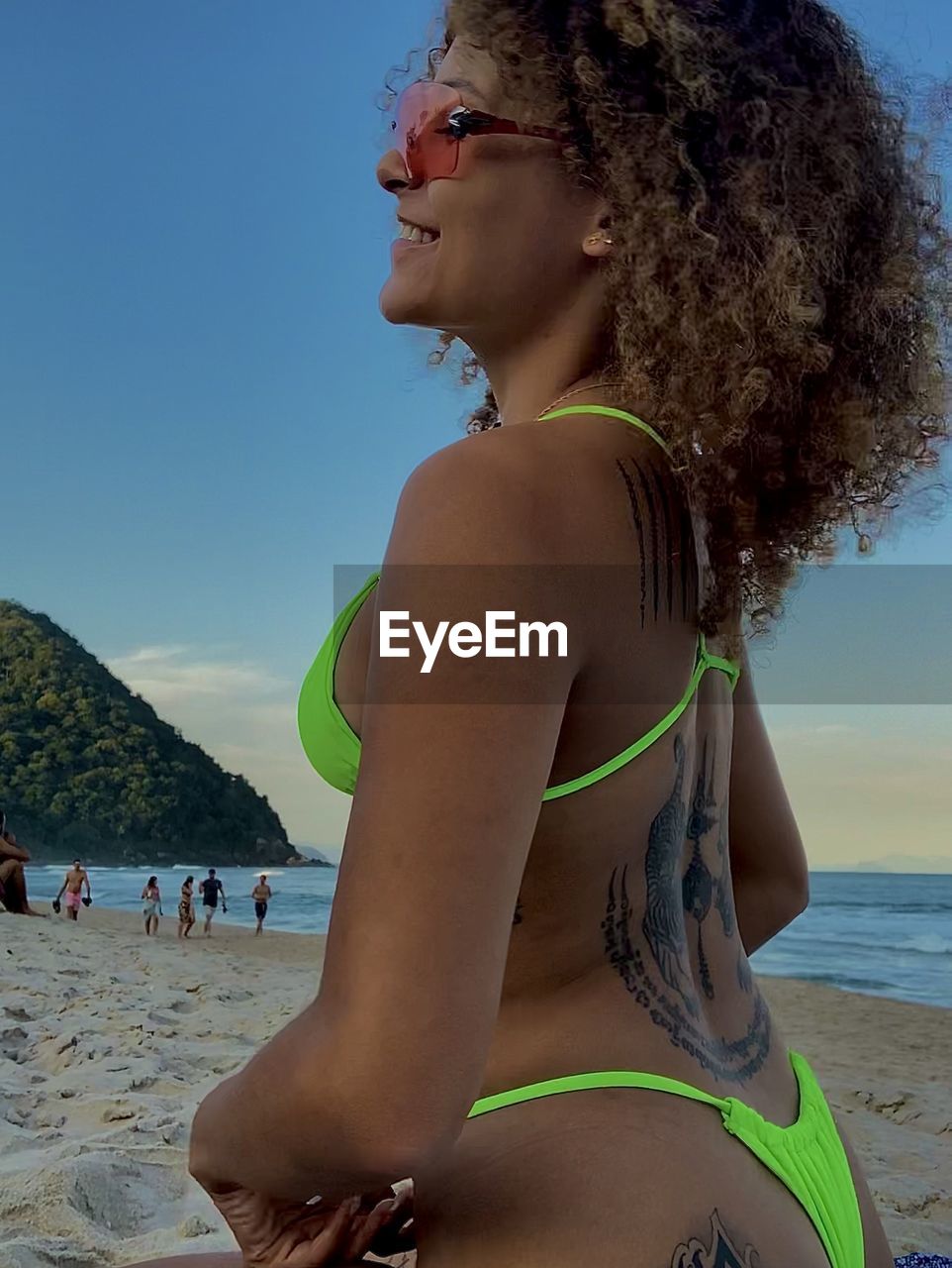 beach, land, adult, water, women, trip, vacation, sun tanning, swimwear, holiday, sea, bikini, summer, clothing, nature, young adult, leisure activity, sky, hairstyle, relaxation, one person, sand, lifestyles, travel, side view, fashion, glasses, smiling, female, curly hair, beauty in nature, day, happiness, sunlight, emotion, human hair, sunglasses, portrait, enjoyment, travel destinations, outdoors, clear sky, blue, looking, person, blond hair, sunbathing, sun, photo shoot, sitting, weekend activities, standing, tropical climate, tourist, long hair, fun, sports, sunny, tranquility, three quarter length, swimsuit top, suntan lotion, waist up