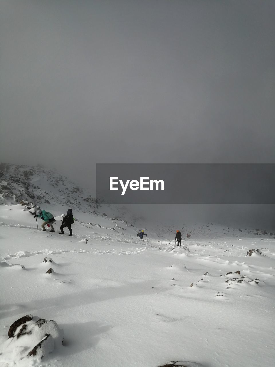 People on snow covered land against sky