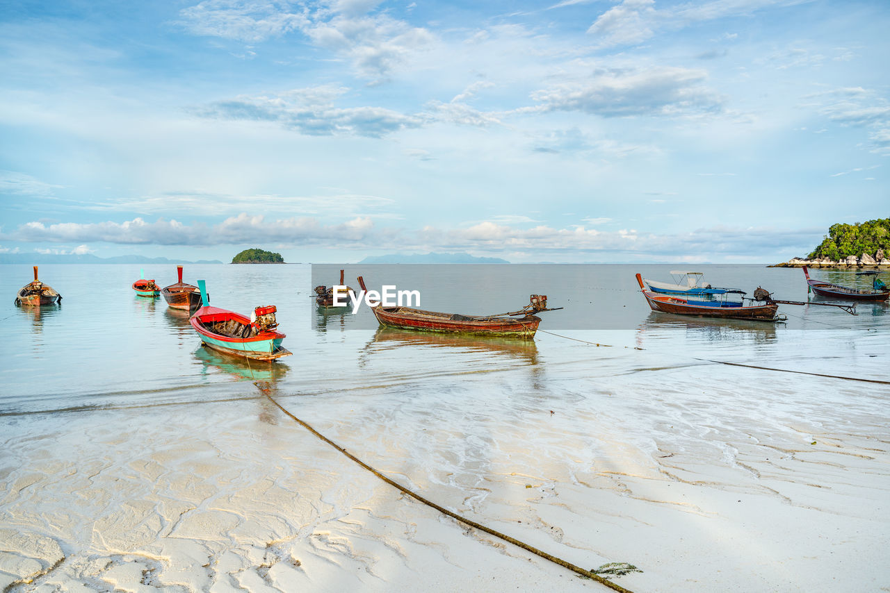 Boats moored on sunrise beach of lipe island. thailand