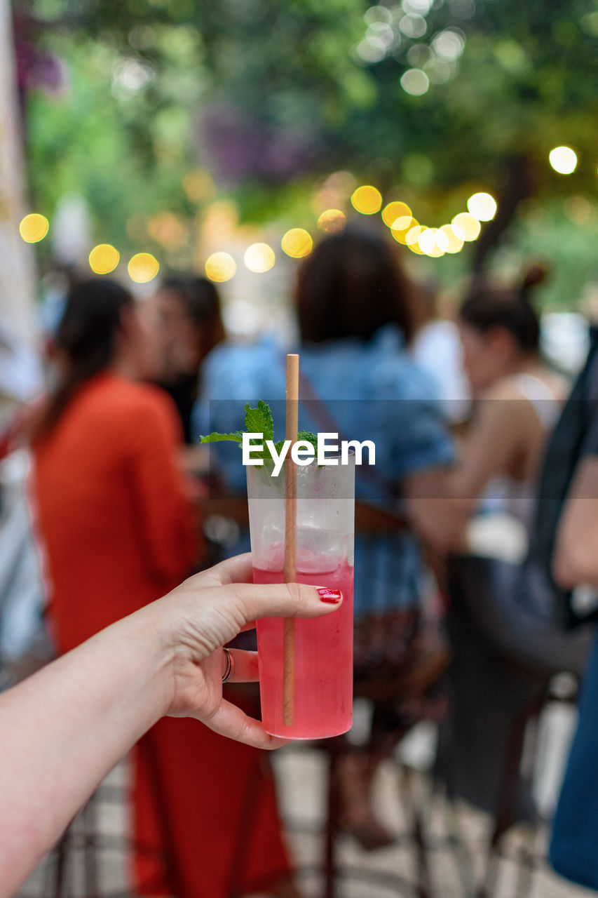 Personal perspective of woman holding cocktail glass with red cocktail