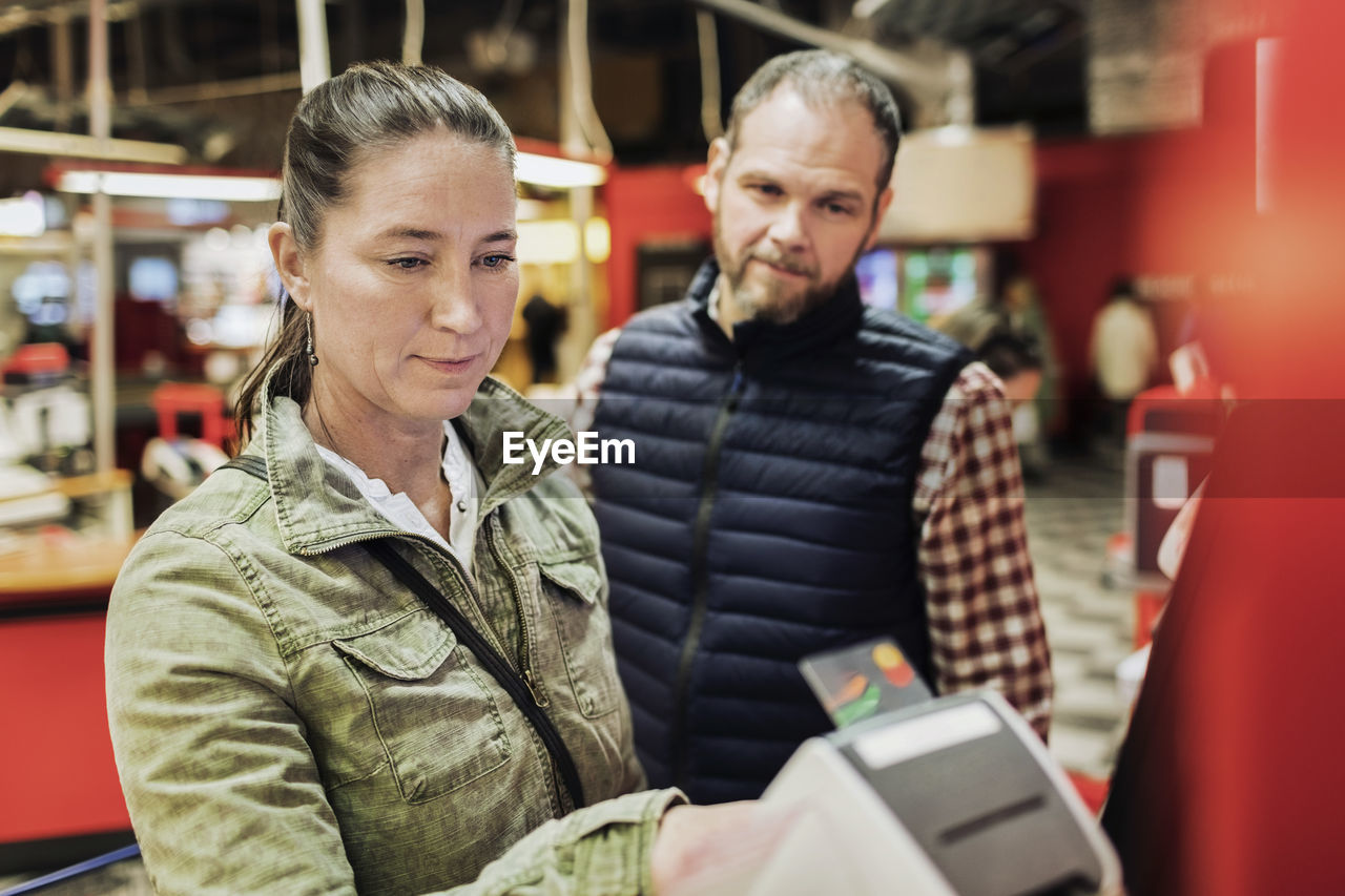 Woman doing payment while standing with man at supermarket