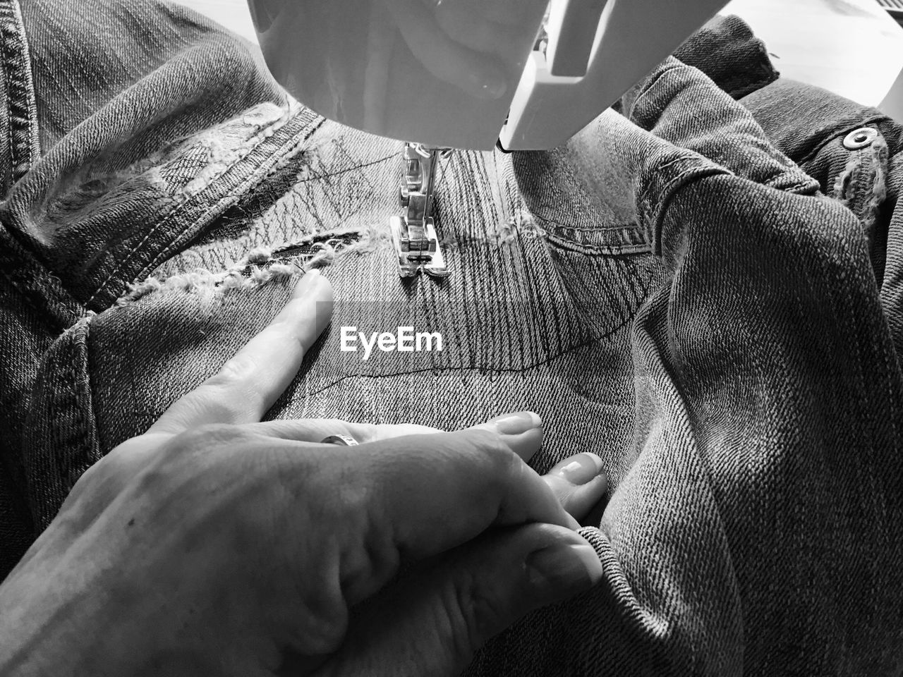 Close-up of woman stitching jeans on sewing machine